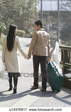 Stock Photo - Japanese couple walking hand in hand, rear view, Japan. Fotosearch