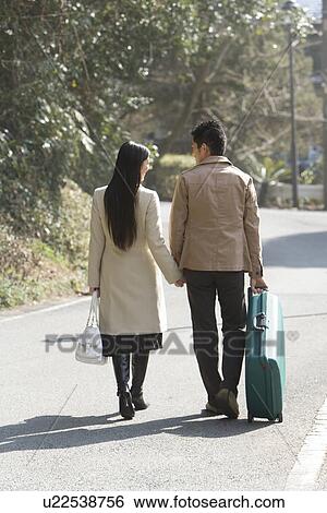 Stock Photograph - Japanese couple walking hand in hand, rear view, Japan. Fotosearch