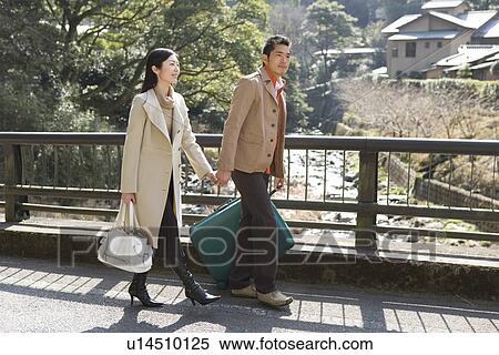 Stock Photography - Japanese couple walking hand in hand, side view, Japan. Fotosearch