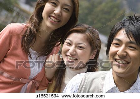 Picture - Portrait of three young people, smiling and looking at camera, front view, Japan. Fotosearch