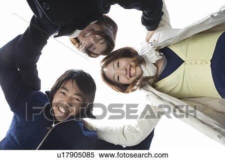 Three young people in huddle, smiling and looking at camera, low angle view, white background, Japan View Large Photo Image Stock Photography - Three young people in huddle, smiling and looking at camera, low angle view, white background, Japan. Fotosearch