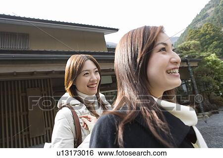 Stock Photograph - Two women in front of the entrance of Japanese inn, side view, Japan. Fotosearch