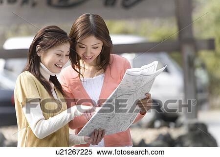 Stock Photography - Two women looking at map on the road, front view, side view, Japan. Fotosearch