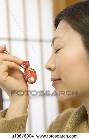 Woman holding a Japanese ornament in the shop of hotel, side view, close up, Japan View Large Photo Image Picture - Woman holding a Japanese ornament in the shop of hotel, side view, close up, Japan. Fotosearch