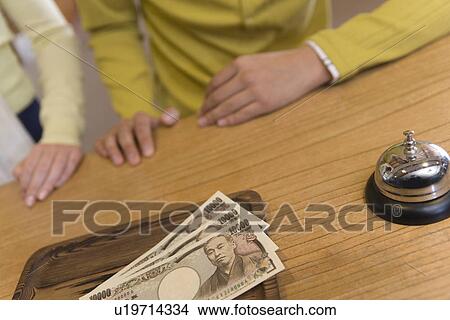 Picture - Young couple at reception, Yen bills on tray, front view, Japan. Fotosearch