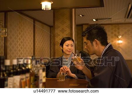 Stock Photo - Japanese couple in Yukata drinking at the hotel bar, front view, side view, Japan. Fotosearch