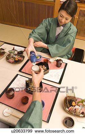Japanese couple in Yukata having dinner, woman pouring Sake, high angle view, Japan View Large Photo Image Stock Photo - Japanese couple in Yukata having dinner, woman pouring Sake, high angle view, Japan. Fotosearch