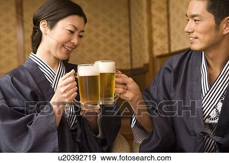 Stock Photo - Japanese couple in Yukata toasting with beer, front view, side view, Japan. Fotosearch