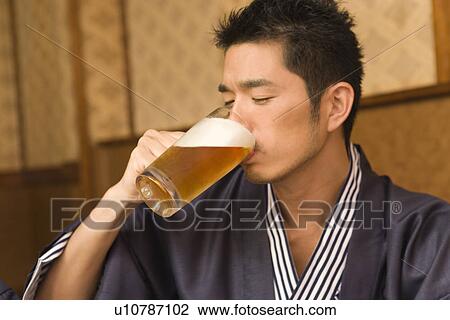 Stock Image - Man in Yukata drinking beer, side view, Japan. Fotosearch