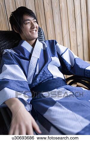 Stock Photograph - Man in Yukata smiling and sitting on chair, front view, Japan. Fotosearch