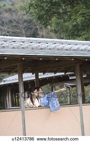 Stock Photograph - Two women in Yukata talking at the outside corridor, front view, Japan. Fotosearch