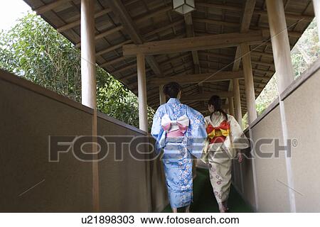 Stock Image - Two women in Yukata walking at the outside corridor, rear view, Japan. Fotosearch
