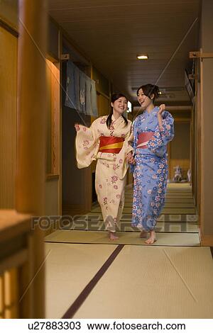 Stock Image - Two women in Yukata walking hand in hand, front view, Japan. Fotosearch