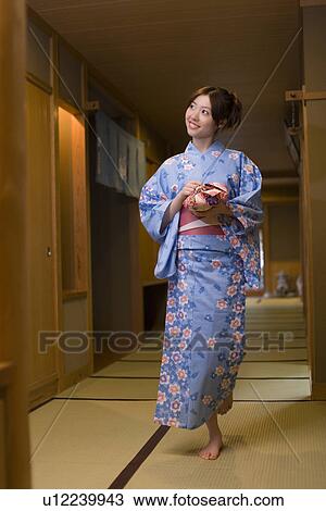 Stock Image - Woman holding wrapped box and walking in Yukata, front view, Japan. Fotosearch