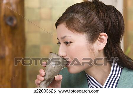 Stock Photography - Woman in Yukata drinking beer, side view, Japan. Fotosearch