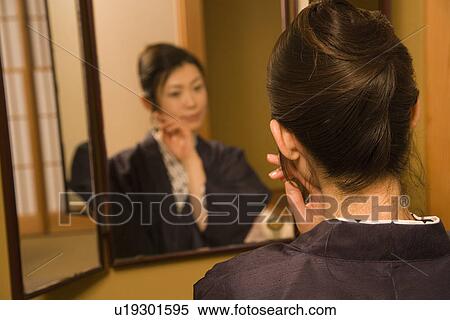 Stock Photography - Woman in Yukata looking into the mirror, rear view, Japan. Fotosearch