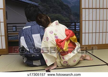 Stock Photo - Young couple in Yukata relaxing in Japanese style room, woman leaning on man, rear view, Japan. Fotosearch