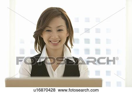 A woman smiling and sitting at desk, front view View Large Photo Image Stock Photo - A woman smiling and sitting at desk, front view. Fotosearch