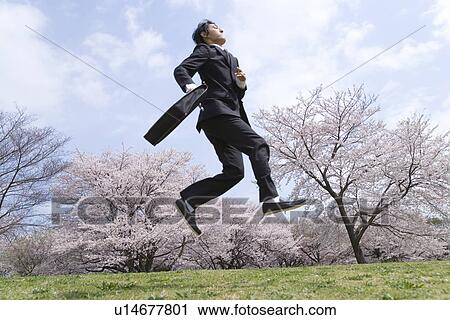 Stock Image - Businessman Jumping in the Field, Full Length, Side View. Fotosearch