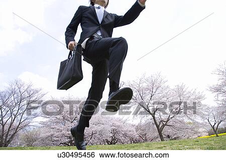 Stock Photograph - Businessman Jumping in the Field, Three Quarter Length, Low Angle View. Fotosearch