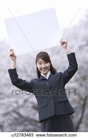 Stock Image - Businesswoman Lifting a White Board, Three Quarter Length, Front View. Fotosearch