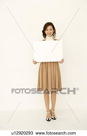 Portrait of a woman smiling and holding a blank board, looking at camera, front view, white background View Large Photo Image Stock Image - Portrait of a woman smiling and holding a blank board, looking at camera, front view, white background. Fotosearch