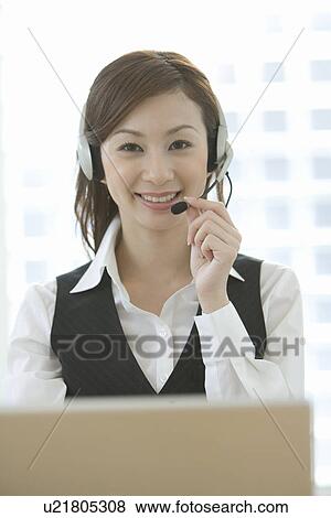 Portrait of a woman wearing a hands-free headset at desk, looking at camera, front view View Large Photo Image Stock Photo - Portrait of a woman wearing a hands-free headset at desk, looking at camera, front view. Fotosearch