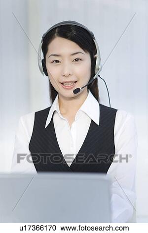 Portrait of a woman wearing hands-free headset and using laptop, looking at camera, front view View Large Photo Image Stock Image - Portrait of a woman wearing hands-free headset and using laptop, looking at camera, front view. Fotosearch