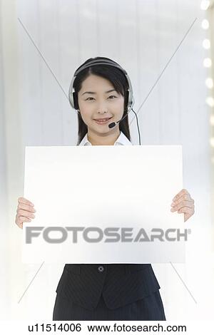 Portrait of a woman wearing hands-free headset and holding a blank board, looking at camera, front view View Large Photo Image Stock Photograph - Portrait of a woman wearing hands-free headset and holding a blank board, looking at camera, front view. Fotosearch