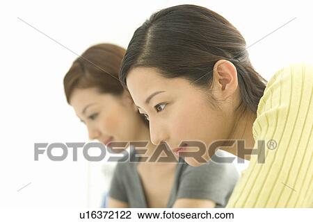 Stock Image - Side view of two women, white background, head and shoulders . Fotosearch