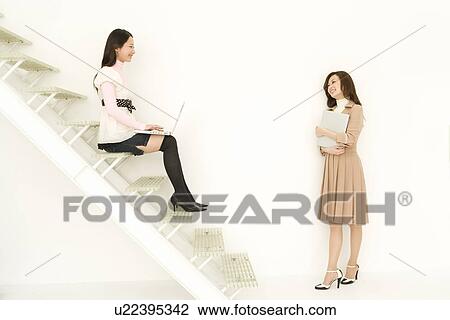 Two women talking at stairs, side view, white background View Large Photo Image Stock Image - Two women talking at stairs, side view, white background. Fotosearch