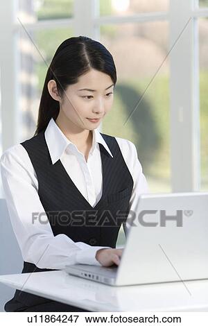 Stock Photo - Woman using laptop in office, side view. Fotosearch