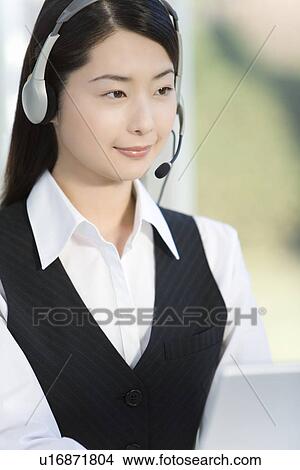 Woman wearing hands-free headset and using laptop, side view View Large Photo Image Picture - Woman wearing hands-free headset and using laptop, side view. Fotosearch