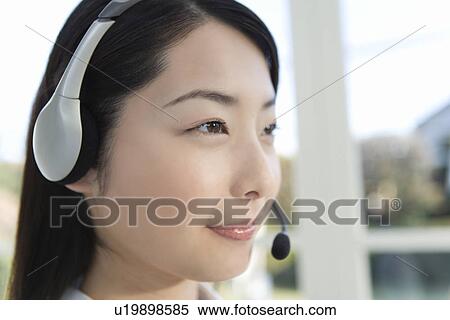 Stock Photography - Woman wearing hands-free headset, side view, close up. Fotosearch