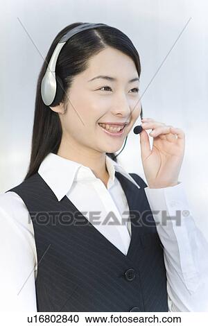 Woman wearing hands-free headset, smiling, side view, white background View Large Photo Image Stock Image - Woman wearing hands-free headset, smiling, side view, white background. Fotosearch