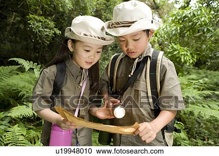Boy and girl in a forest looking at map View Large Photo Image Stock Image - Boy and girl in a forest looking at map. Fotosearch
