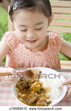 Stock Image - Girl eating curry. Fotosearch