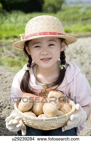 Picture - Girl holding potatoes and carrot in a basket. Fotosearch
