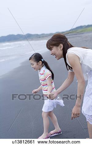 Stock Image - Mother and daughter playing at beach. Fotosearch
