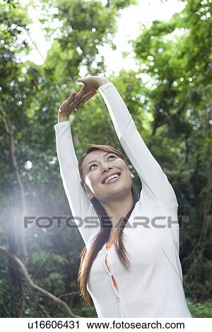 Stock Image - Woman stretching in forest. Fotosearch