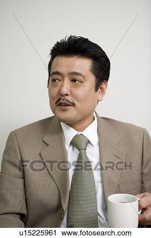 Stock Image - Businessman holding cup of coffee. Fotosearch