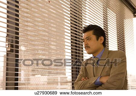 Stock Photo - Businessman looking through blinds. Fotosearch