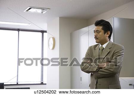 Stock Image - Businessman standing with arms crossed. Fotosearch
