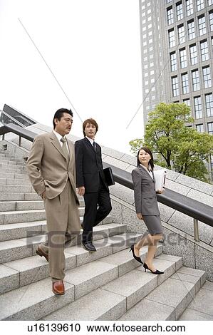 Stock Image - Three business people descending steps. Fotosearch