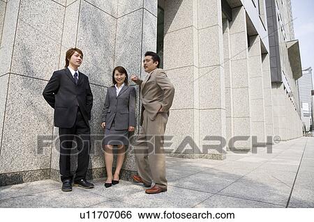 Stock Photograph - Three business people standing outside. Fotosearch