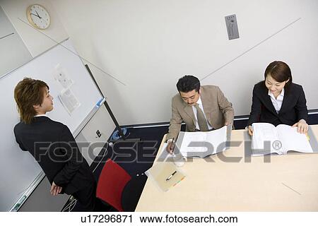 Stock Image - Three people discussing in meeting room. Fotosearch