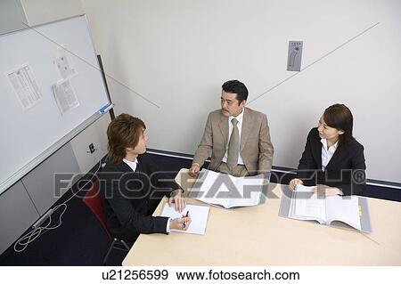 Stock Photo - Three people discussing in meeting room. Fotosearch