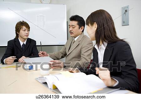 Stock Photo - Three people discussing in meeting room. Fotosearch