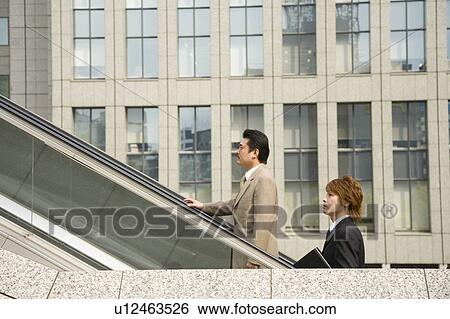 Two Businessmen ascending escalator View Large Photo Image Stock Photograph - Two Businessmen ascending escalator. Fotosearch