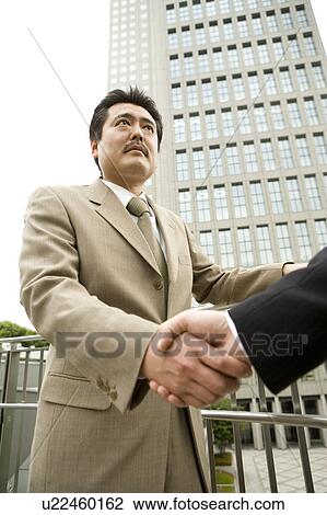 Stock Image - Two businessmen shaking hands. Fotosearch